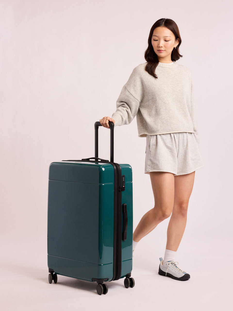 Woman with CALPAK Hue Large Luggage in dark green Kale; LHU1028-GLAZED-KALE