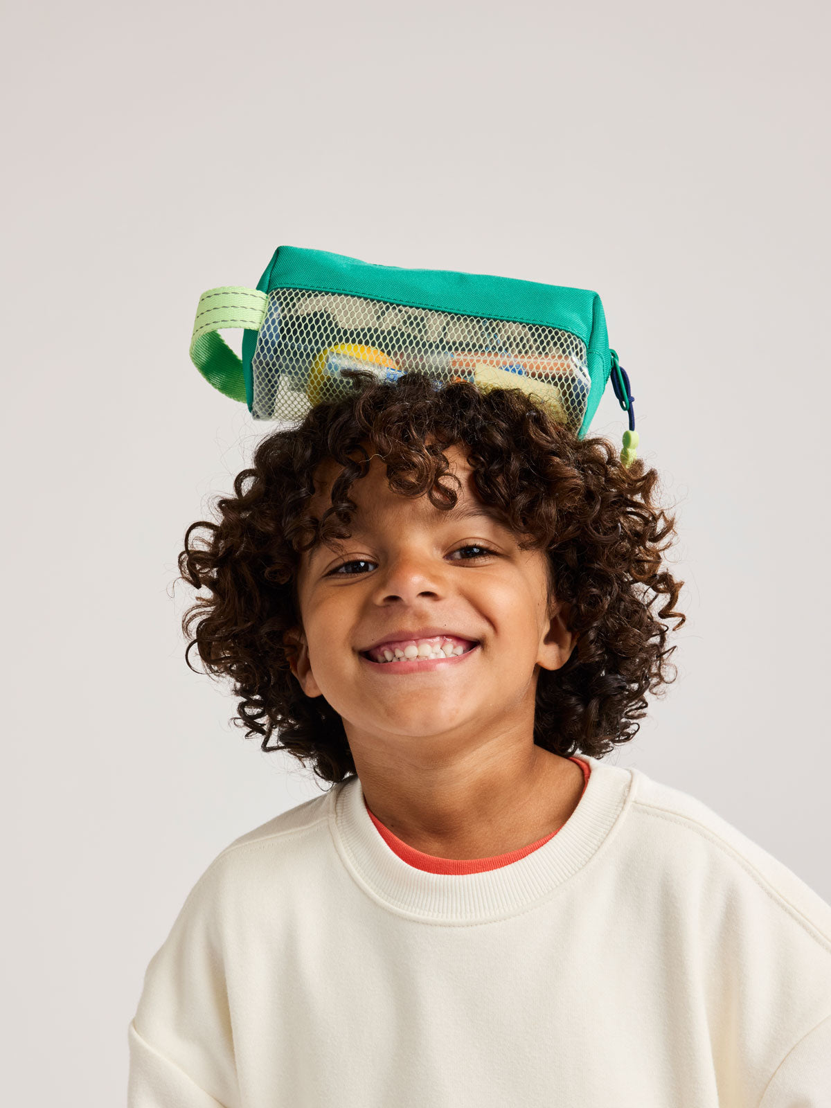 Child with Green CALPAK Kids Pencil Case with lime green accents and mesh bottom on a white background; CKPC2501-GREEN