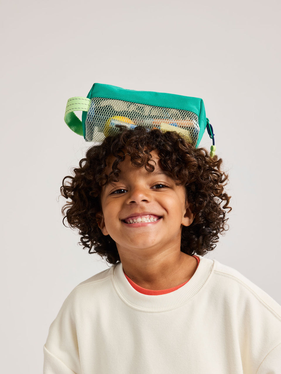 Child with Green CALPAK Kids Pencil Case with lime green accents and mesh bottom on a white background; CKPC2501-GREEN