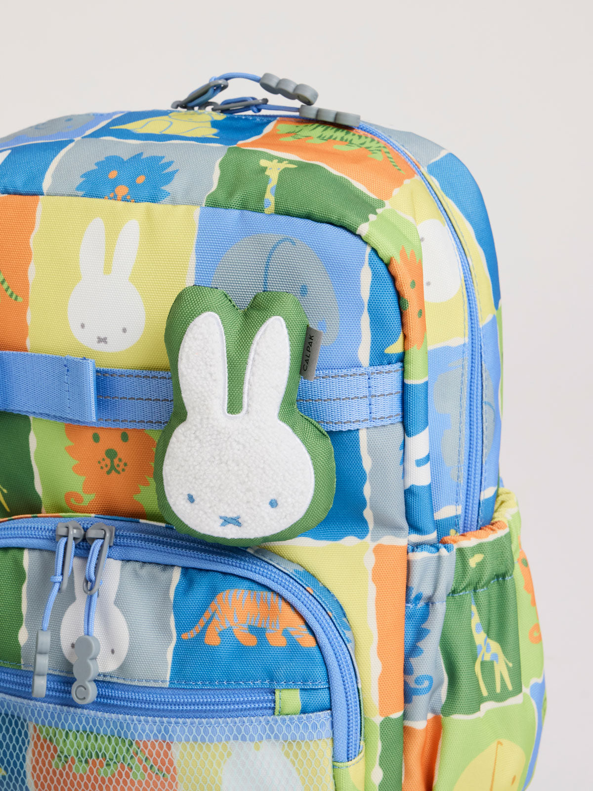 Plush Miffy x CALPAK Pluffy Bag Charm keychain with a green border and Miffy attached to a colorful children CAKPAK Kids Backpack; APLF2501-GREEN-MIFFY
