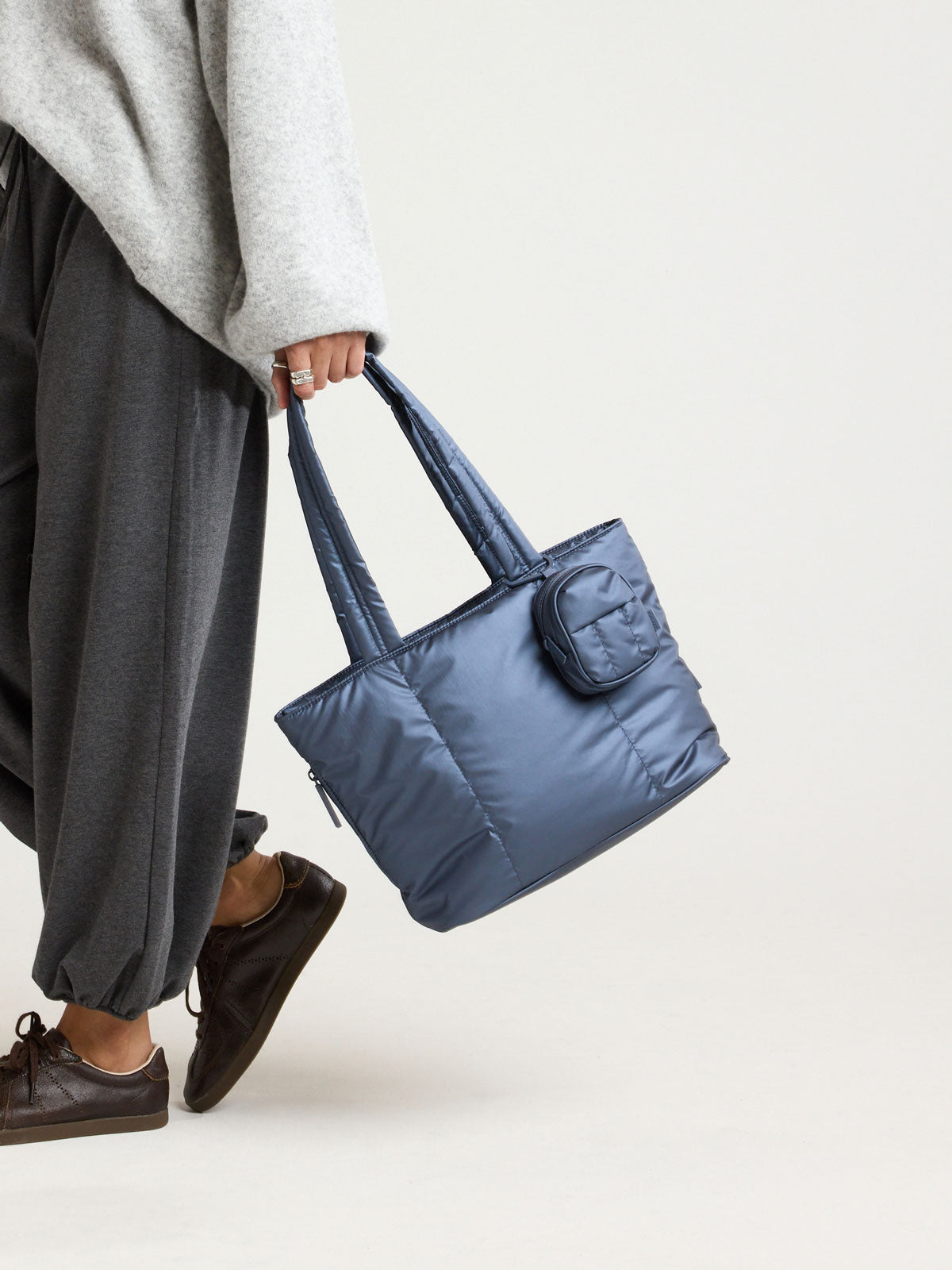 Model carrying a bag with the CALPAK Luka Backpack Zip Bag Charm in metallic dark blue Metallic Indigo clipped; AMB2201-METALLIC-INDIGO