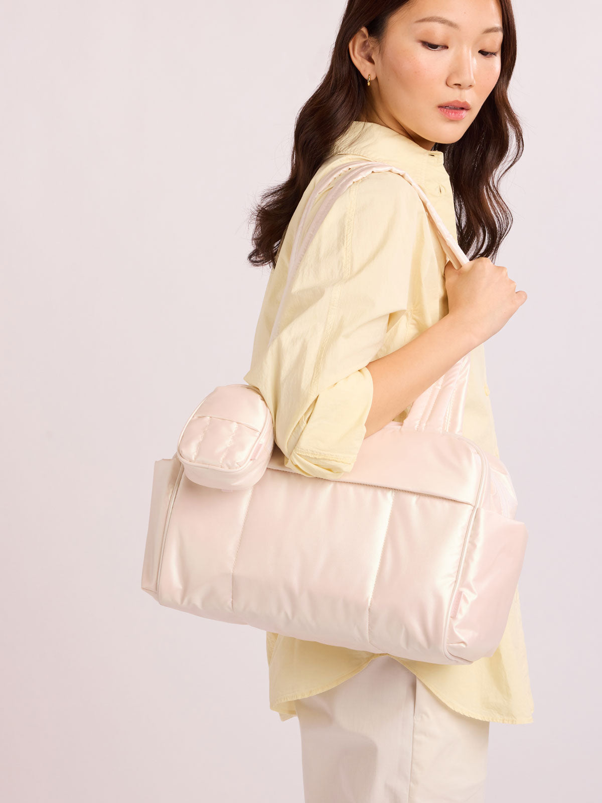 Woman wearing bag with CALPAK Luka Backpack Zip Bag Charm in light pink Pearlescent; AMB2201-PEARLESCENT