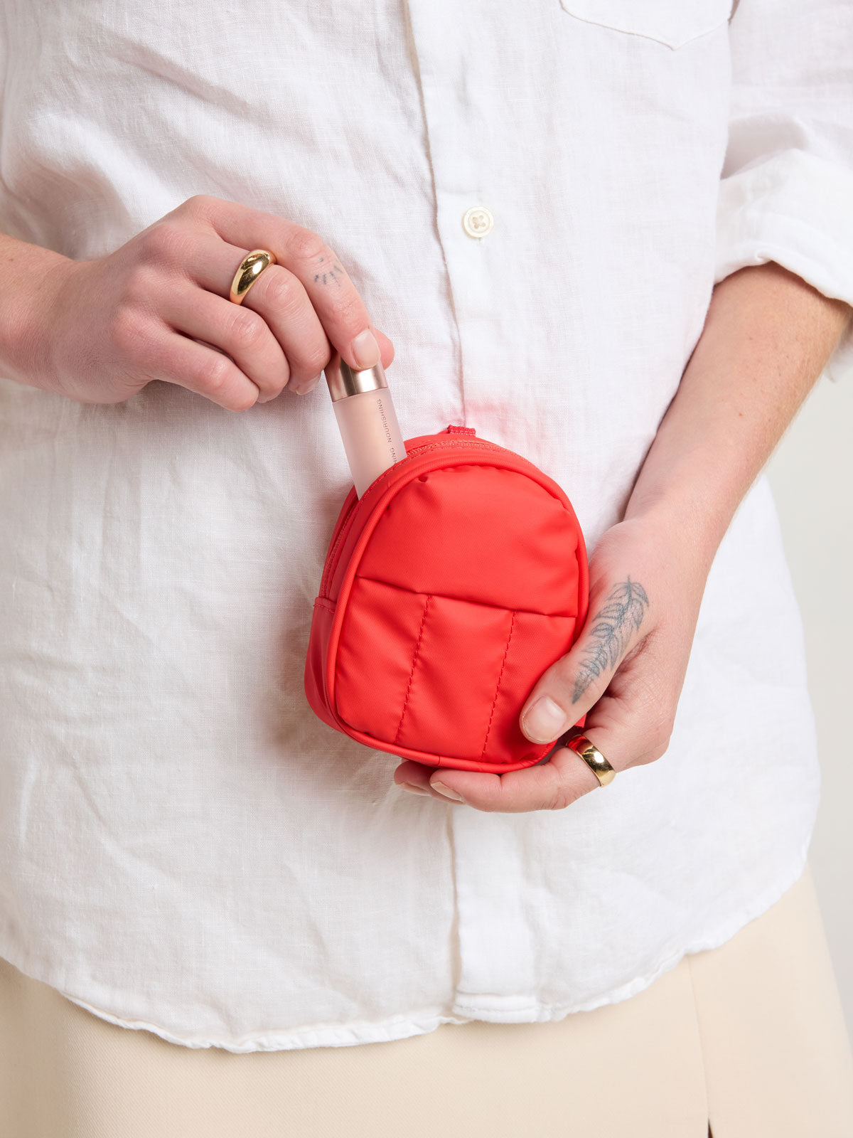Person holding CALPAK Luka Backpack Zip Bag Charm in red Tomato; AMB2201-TOMATO