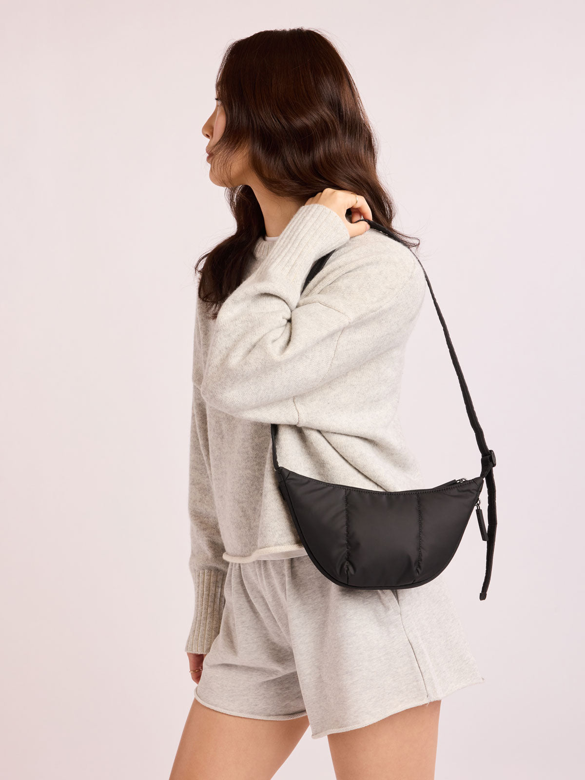 Model with grey outfit wearing CALPAK Luka Crescent Bag in Black; CBL2601-MATTE-BLACK
