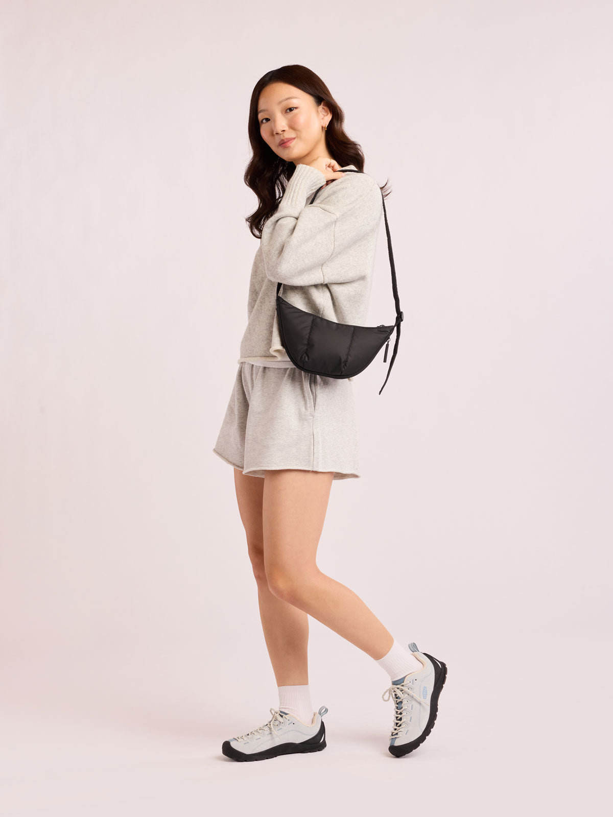Model with grey outfit wearing CALPAK Luka Crescent Bag in Black; CBL2601-MATTE-BLACK