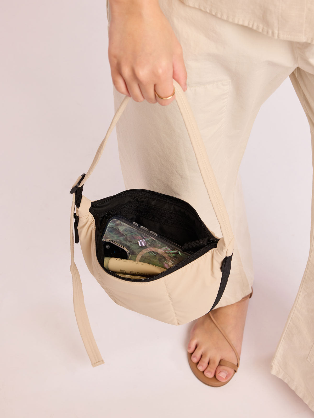 Model holding Model with beige outfit wearing CALPAK Luka Crescent Bag in beige off white Oatmeal; CBL2601-OATMEAL