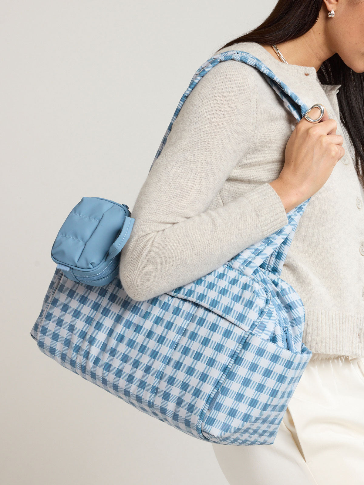 Model with the CALPAK Luka Duffel Zip Bag Charm in light blue French Blue; ALK2501-FRENCH-BLUE