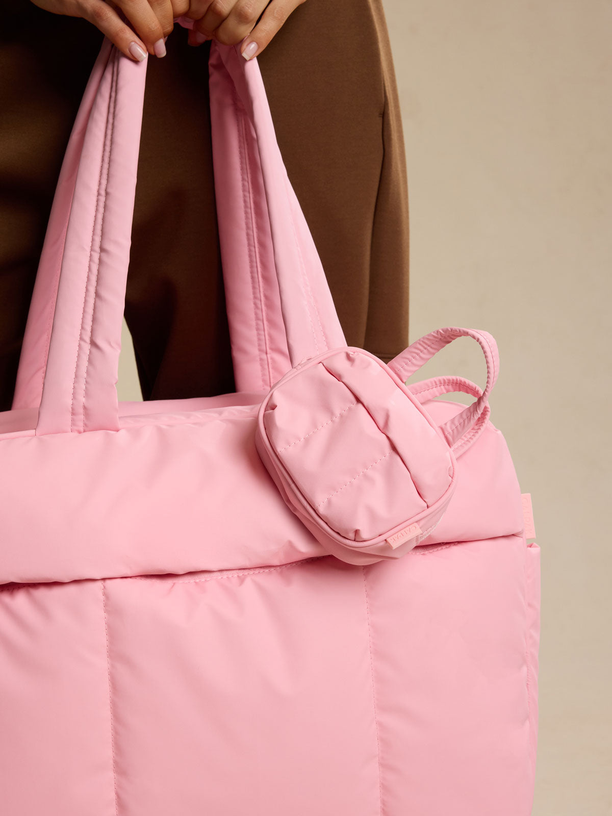 CALPAK Luka Duffel Key Pouch attached to a bag, held by a person against a neutral background; ALK2501-BLOSSOM