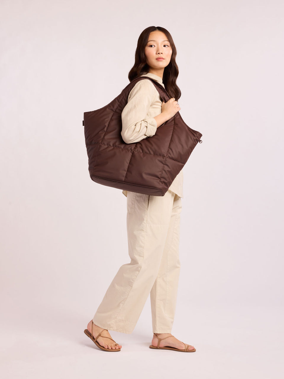 Model wearing CALPAK Luka Everything Laptop tote in brown Walnut with shoulder strap on a white background; AET2601-WALNUT