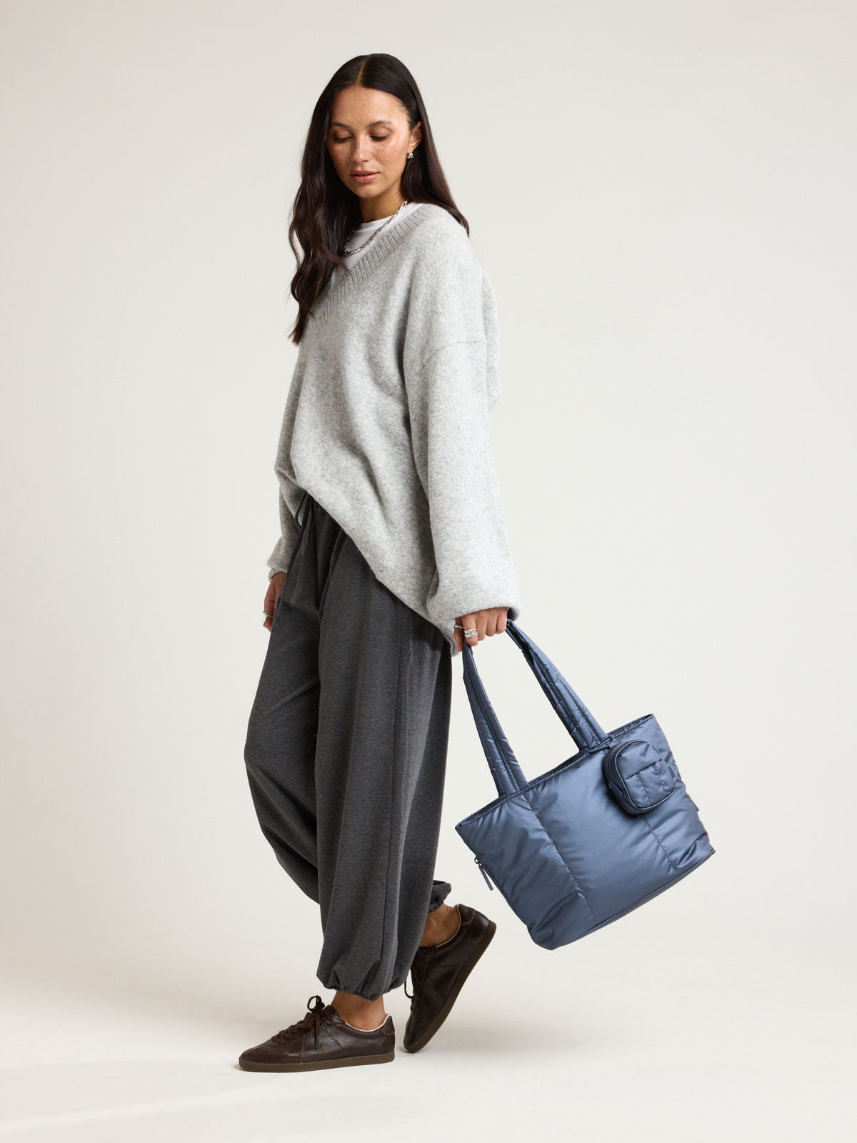 Woman holding CALPAK Luka Mini Tote in metallic dark blue material in Metallic Indigo; ALM2401-METALLIC-INDIGO