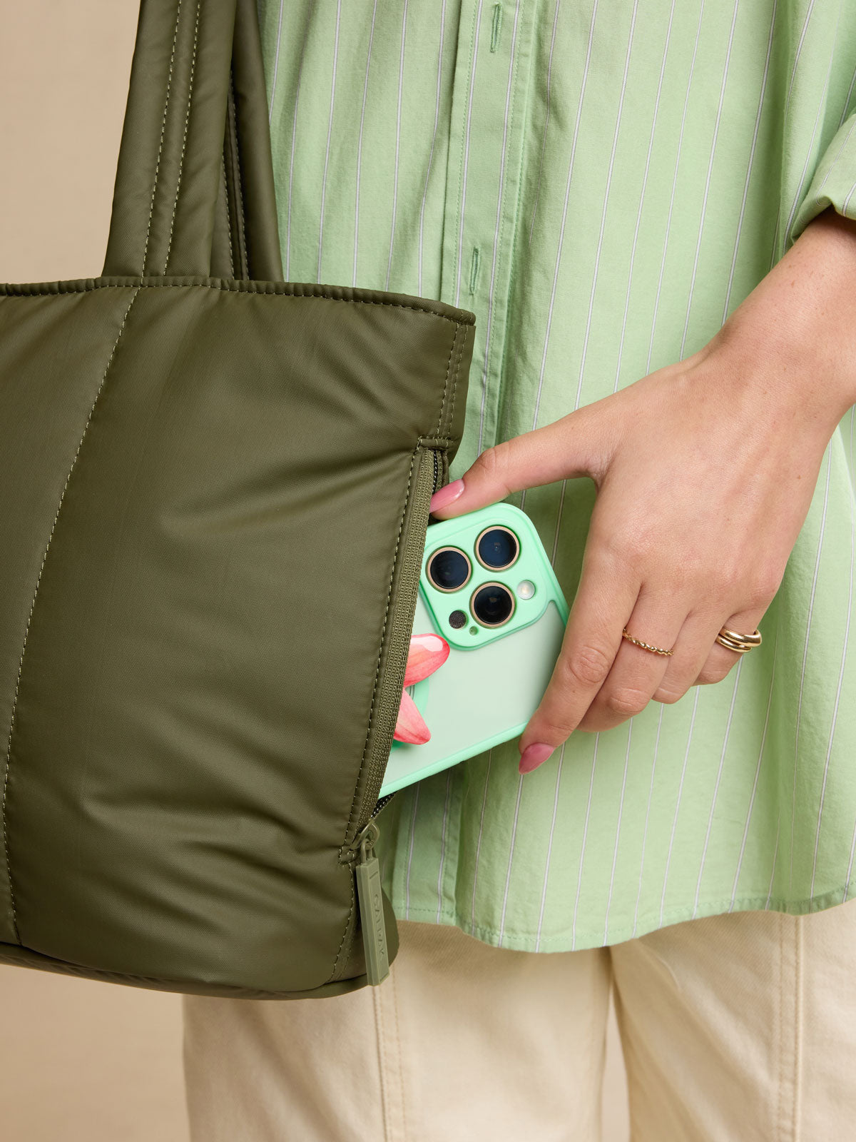 Model putting phone in side pocket of CALPAK Luka Mini Tote in dark green Pine; ALM2401-PINE
