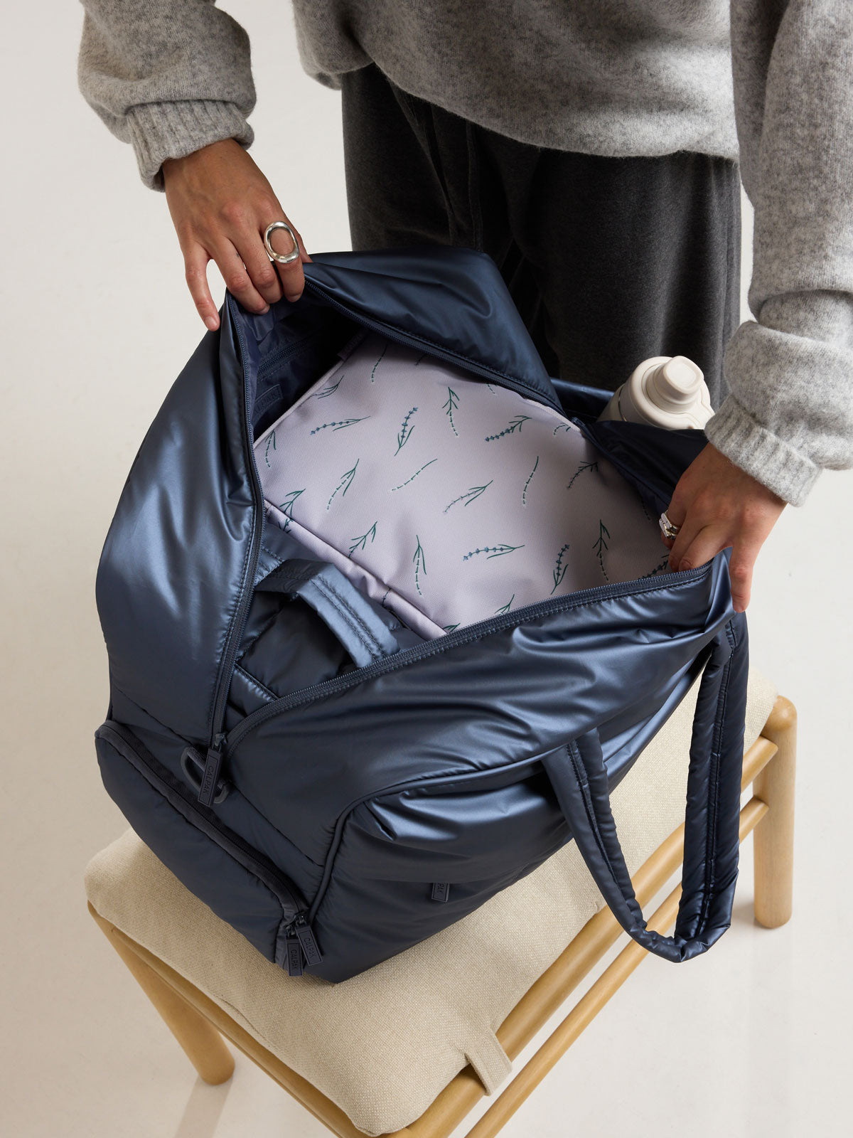 Model packing the CALPAK Medium Compression Packing Cubes (Set of 2) in light purple with lavender print in Lavender Bloom; PCC2201-LAVENDER-BLOOM