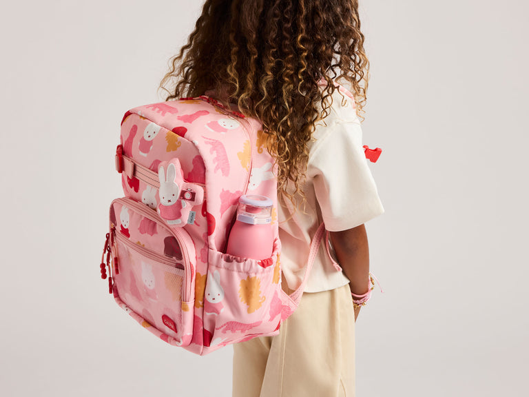 Child model wearing pink CALPAK Miffy Kids Backpack on back with water bottle in side pocket