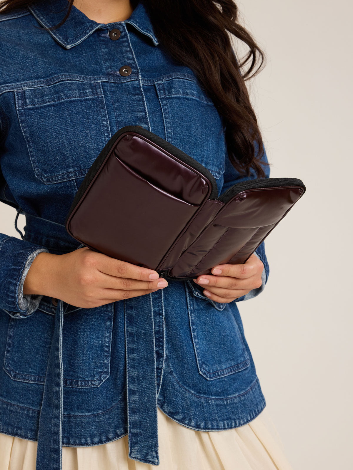 Model with opened CALPAK Luka Zippered Passport Wallet in maroon Glazed Dark Cherry; PZW2301-GLAZED-DARK-CHERRY