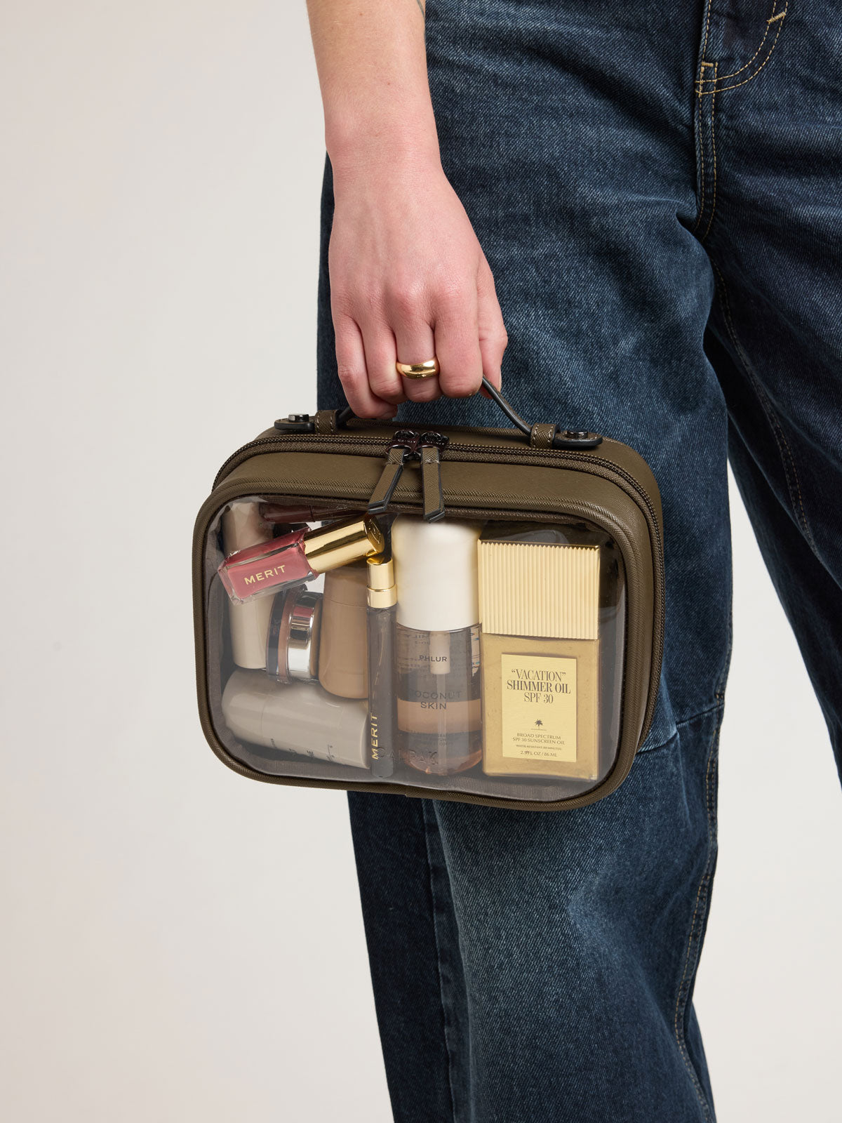 Person holding CALPAK Small Clear Cosmetics Case in brown Mushroom; CCM2001-MUSHROOM