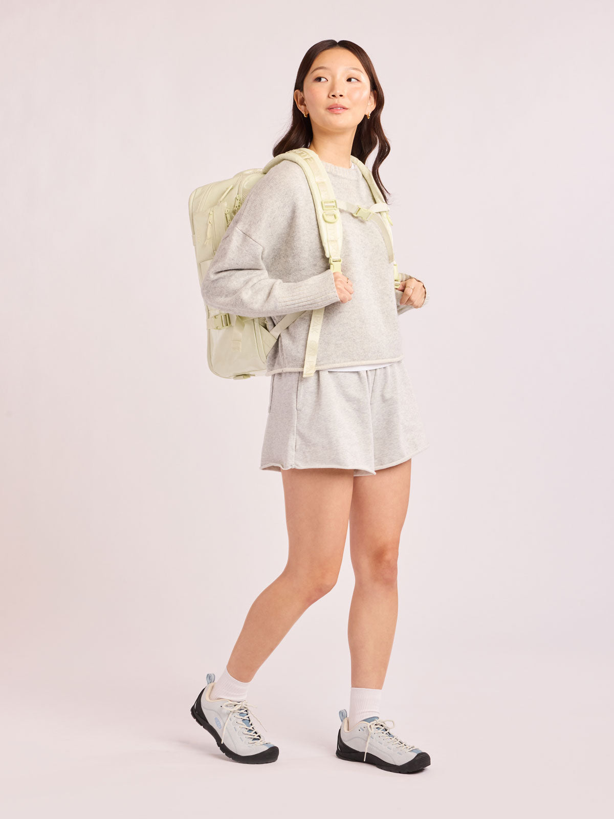 Model wearing the CALPAK Terra 26L Laptop Duffel Backpack with multiple pockets in light green Celadon on a white background; BPH2201-CELADON