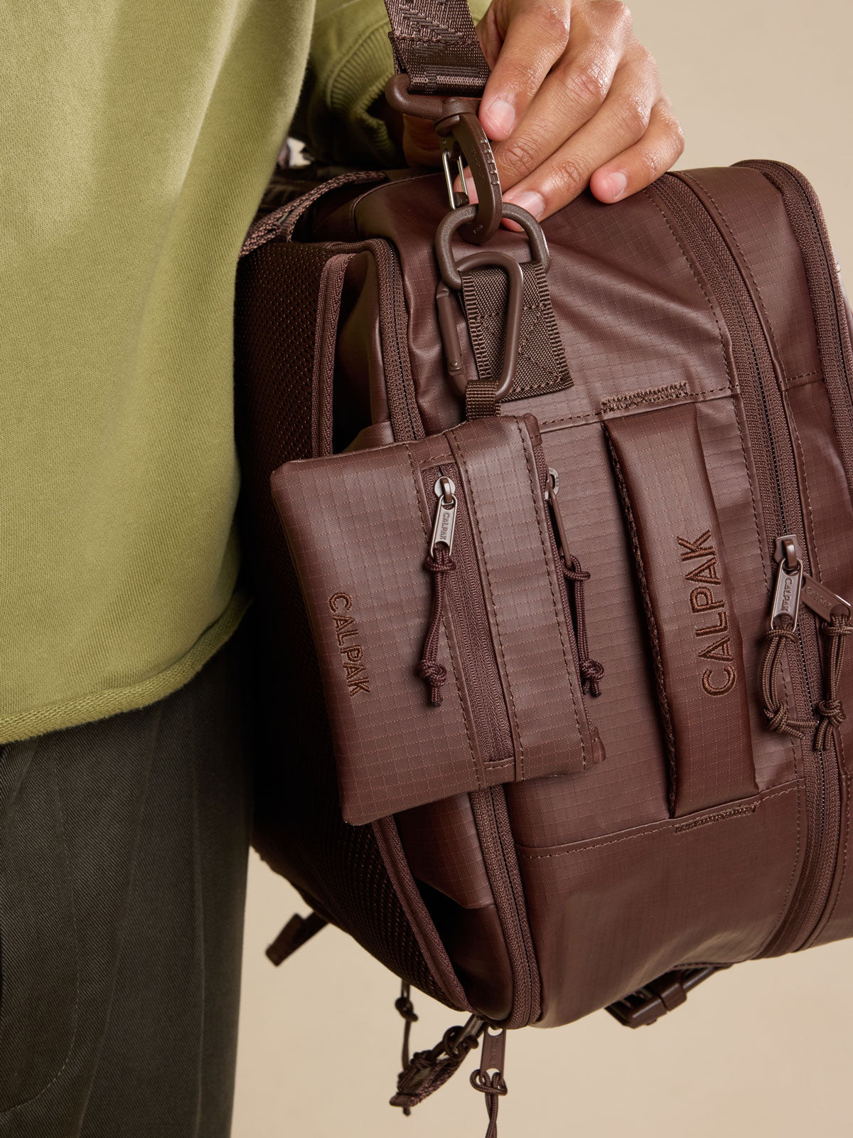 Model with CALPAK Terra Clippable Card Pouch in brown Walnut clipped to bag; TPC2401-WALNUT