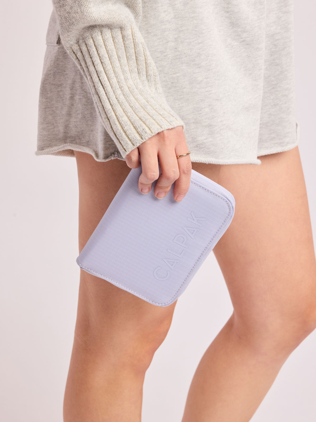 Model holding Front side of CALPAK Terra Zip Passport Wallet in light purple Sea Glass ; ATPW2501-SEA-GLASS