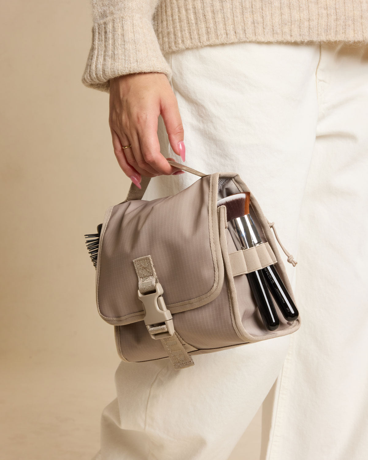 Model holding CALPAK Terra Hanging Toiletry Bag in beige Stone ; THY2201-STONE