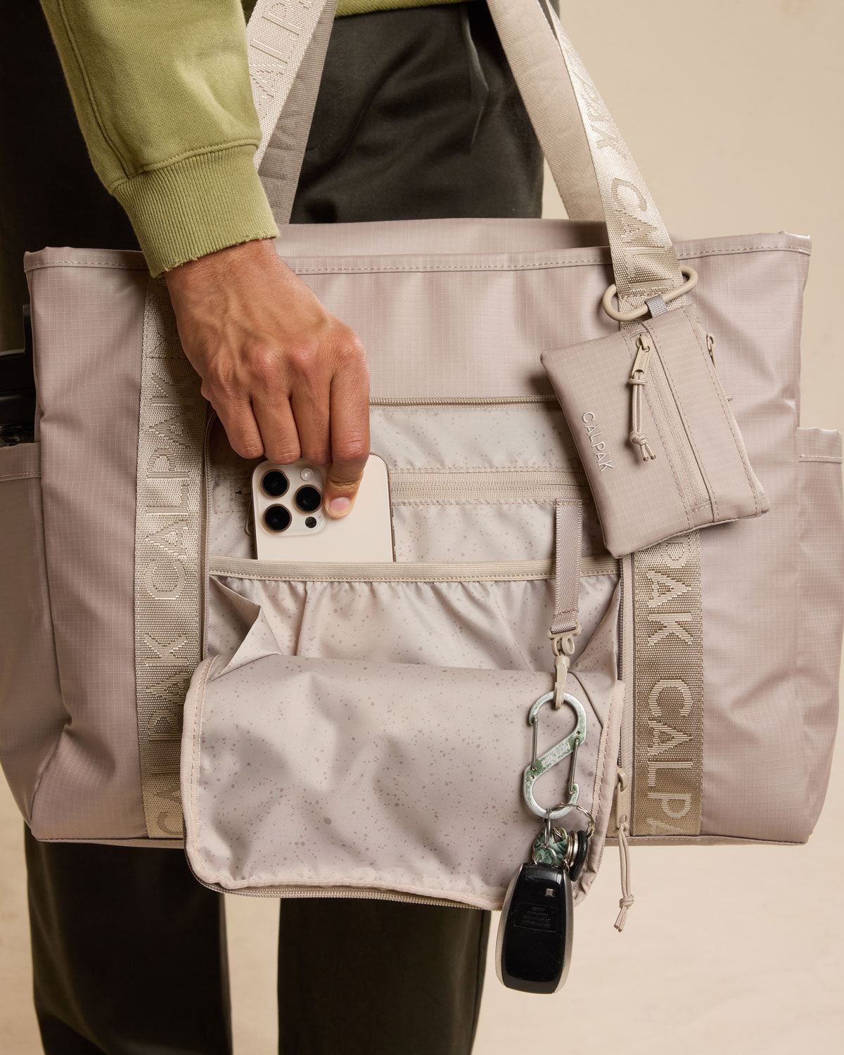 Model using CALPAK Terra 35L Tote in beige Stone front; TTO2401-STONE