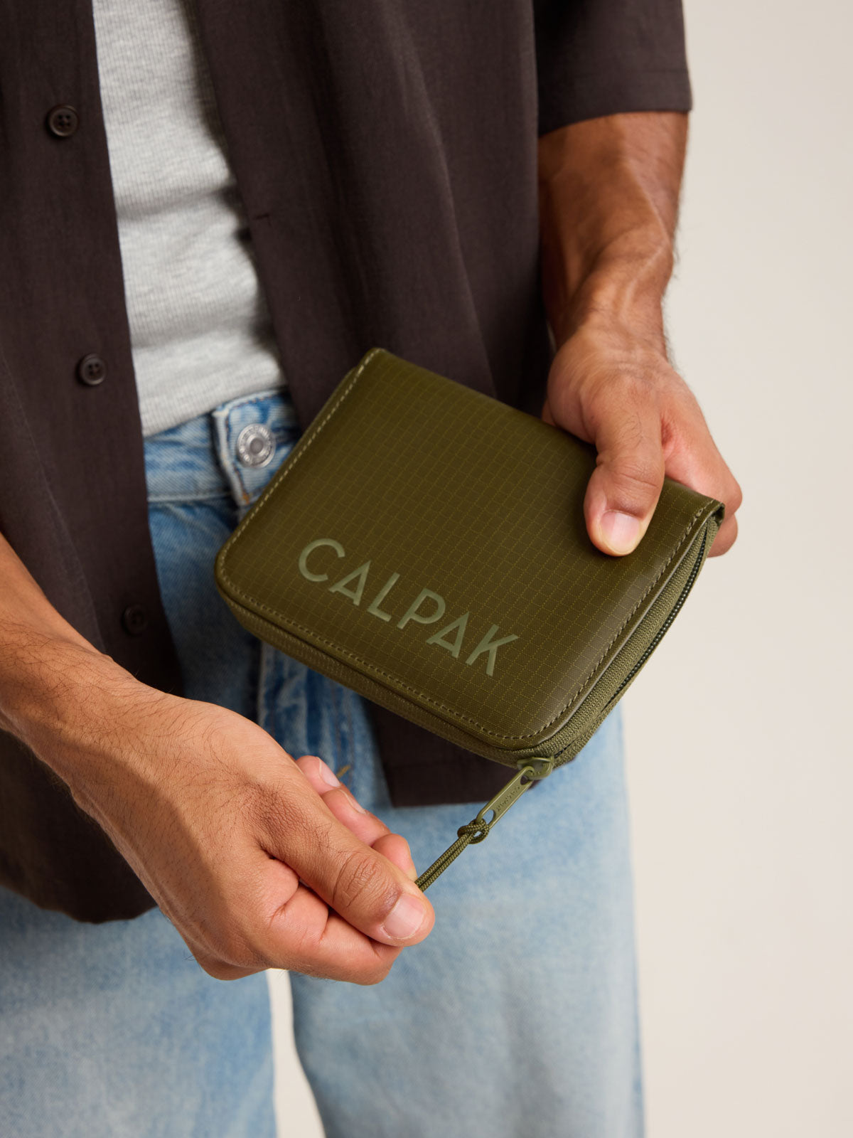 Model with CALPAK Terra Zip Passport Wallet in green Pine; ATPW2501-PINE