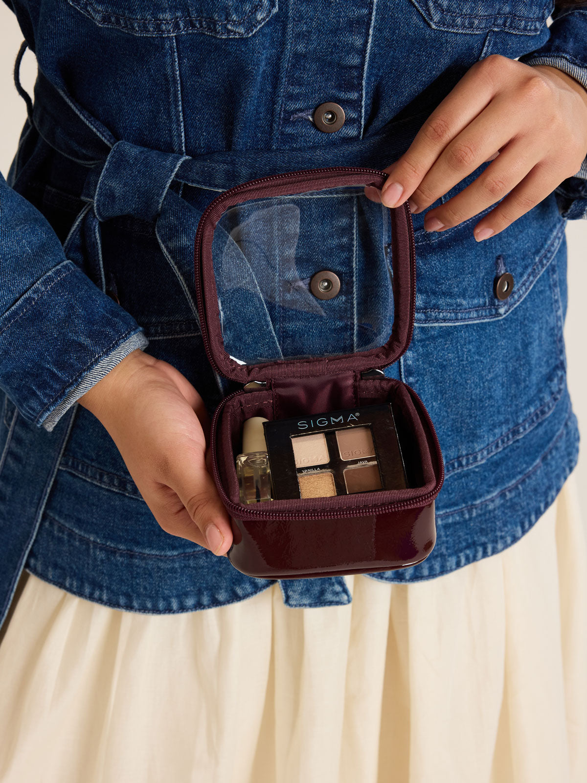 Model with CALPAK Tiny Clear Cosmetics Case in maroon Dark Cherry with makeup inside; CCT2501-GLAZED-DARK-CHERRY