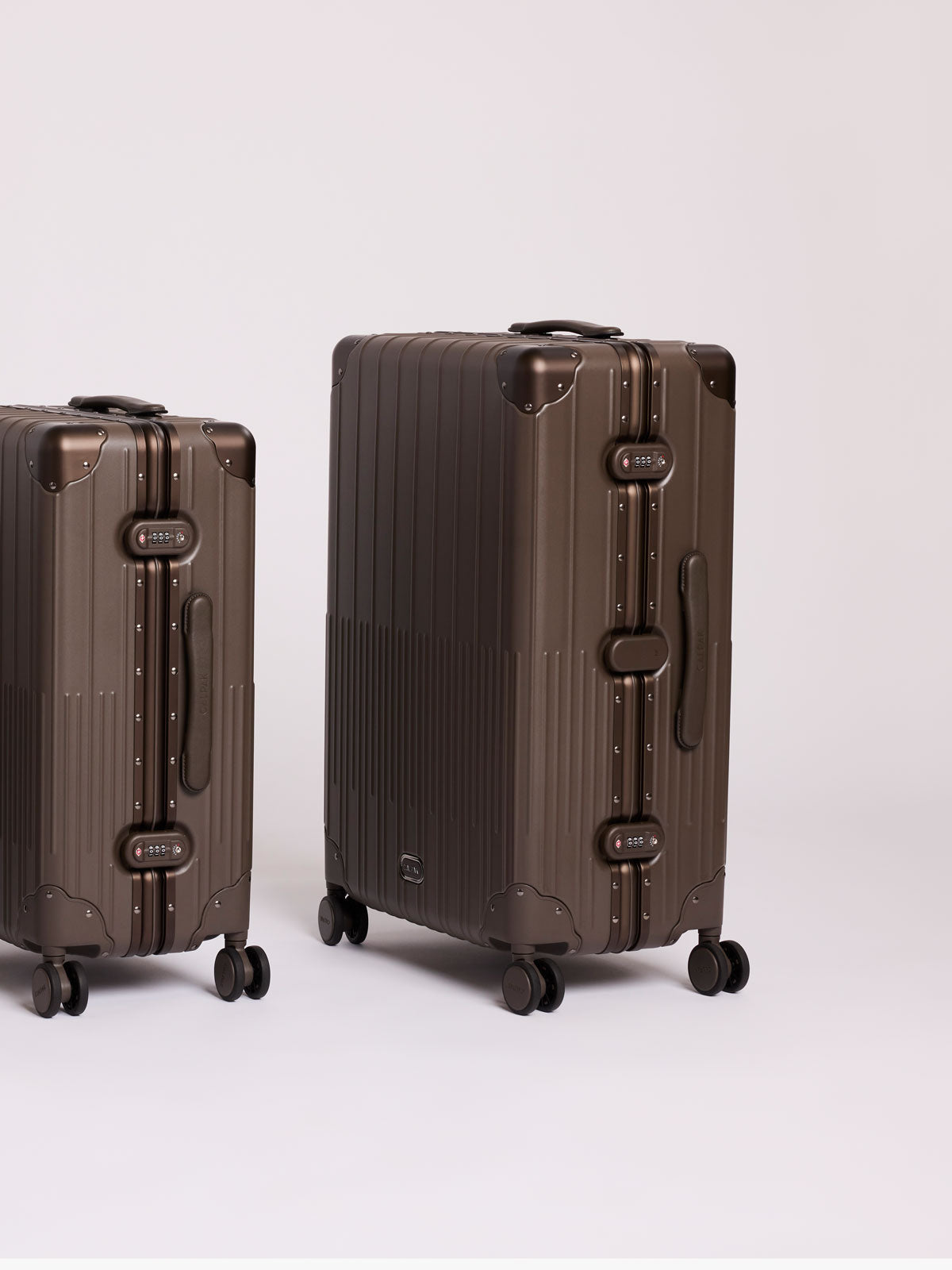 Two ribbed hard-shell CALPAK Medium and Large Vault Luggage in brown Mushroom with hard-shell spinner suitcase with a ribbed vertical design, shown from the front on a light gray background; LVT1028-MUSHROOM