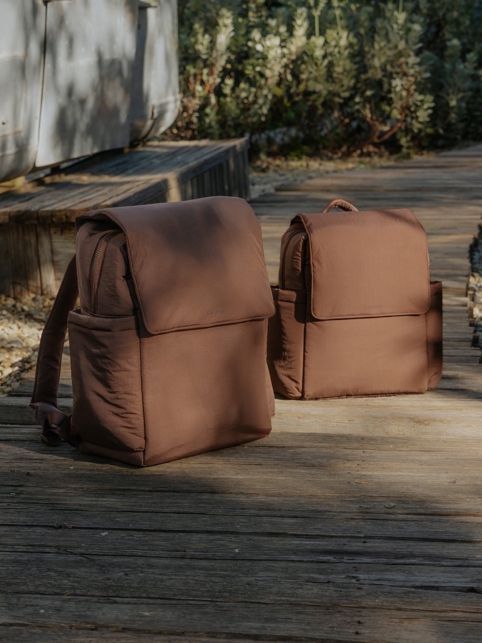 CALPAK Diaper Backpack and  Mini Diaper Backpack in brown Hazelnut in a nature background; BPC2402-HAZELNUT